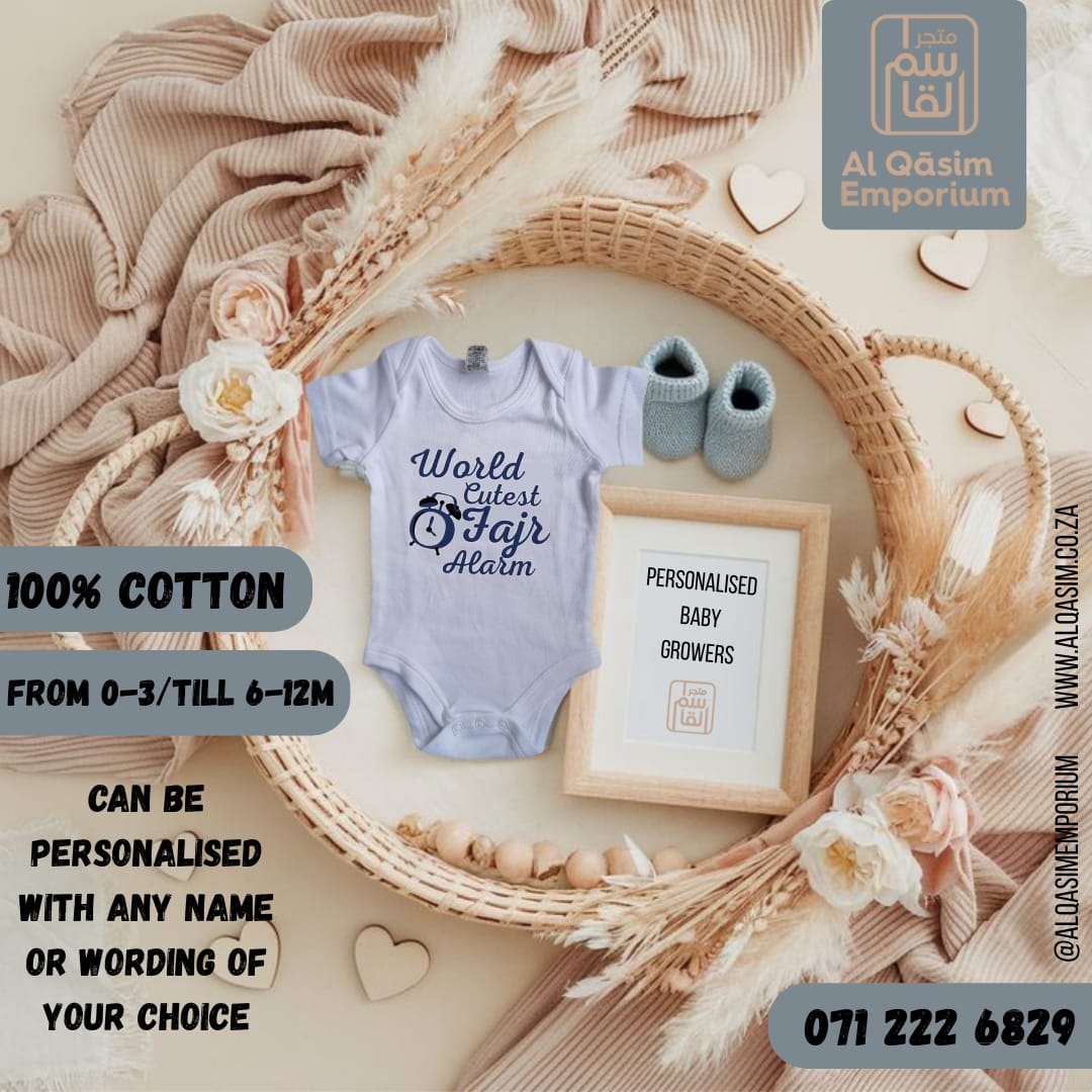 Baby onesie with 'World's Coolest Fajar Alalm' text, baby shoes, and framed picture on a decorative background with 'Al Qasim Emporium' branding.